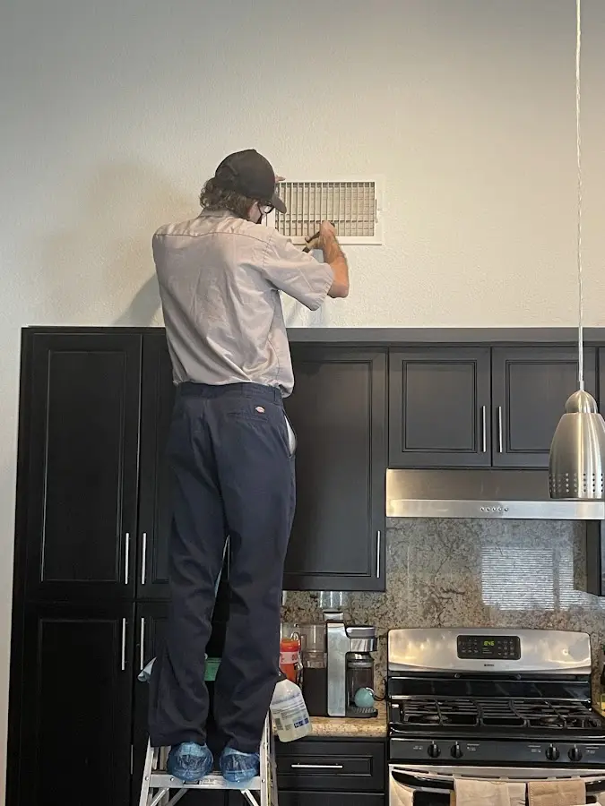 Technician inspecting an air vent during HVAC service in South Venice